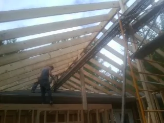 Rafters going up over a new addition with a worker on the wall in Flintville