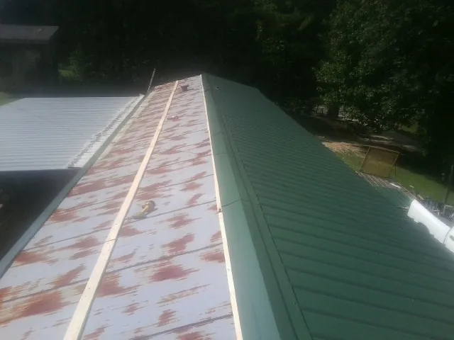 Old rusted panels beside newly installed green metal roofing — Wind Damage Roof Repair by Roofing Brothers in Flintville