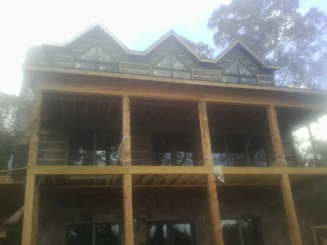 Dormers and porch framing on a large log home under construction — Roof Coating work by our crew in Flintville