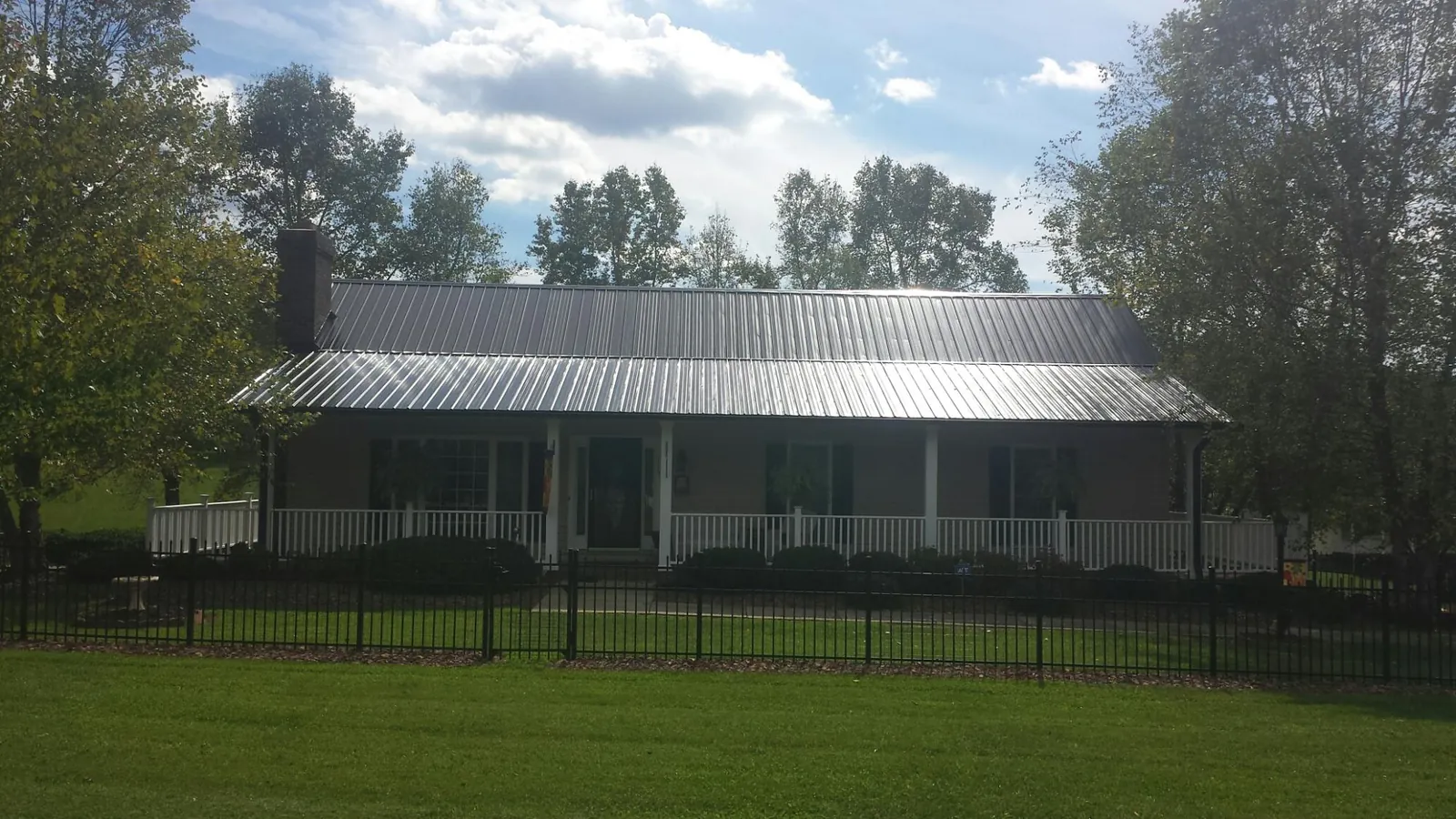 Gray metal roof on a brick ranch with a full width front porch — Gutter Guard Installation work by our crew in Flintville