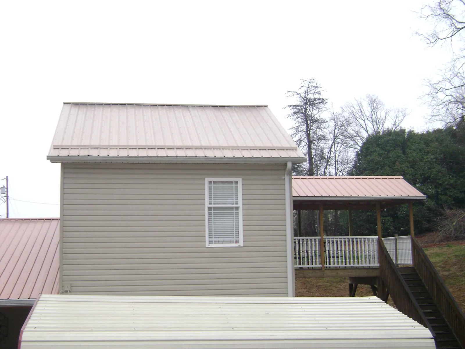 Tan metal roofs on a two story addition and attached porch, from a Roof Replacement job in Flintville