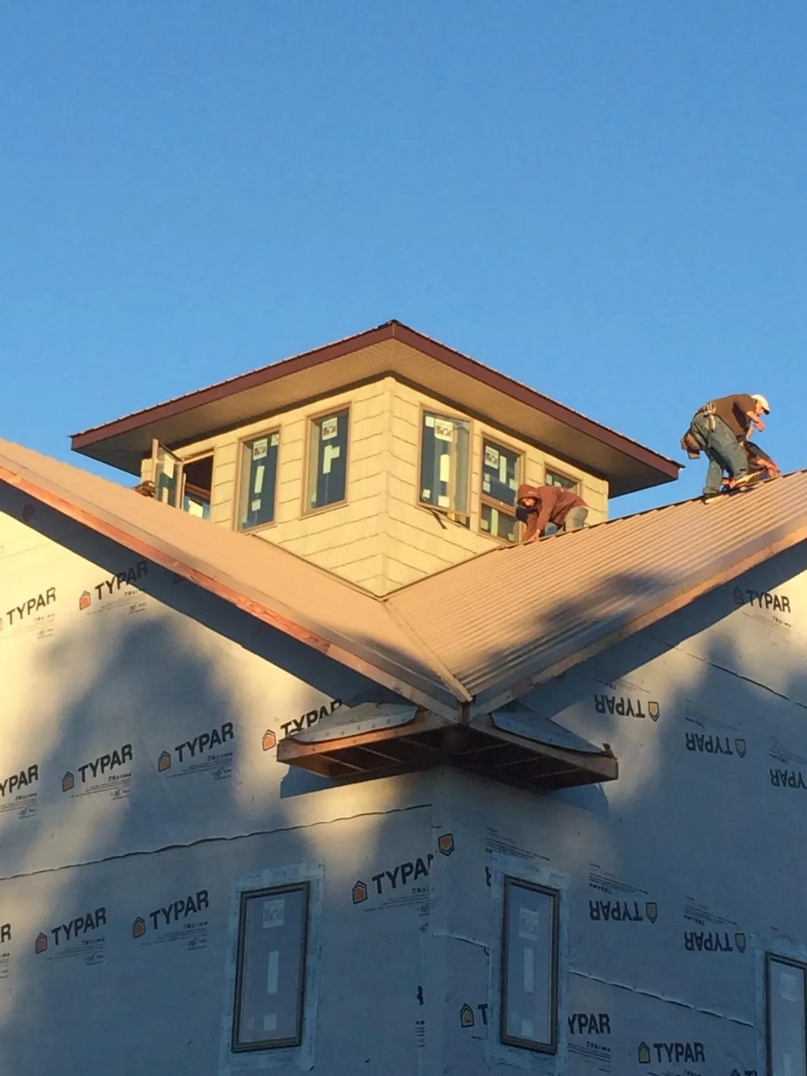 Roofers working around a rooftop cupola on a new metal roof at sunset — Roof Waterproofing in Flintville by Roofing Brothers